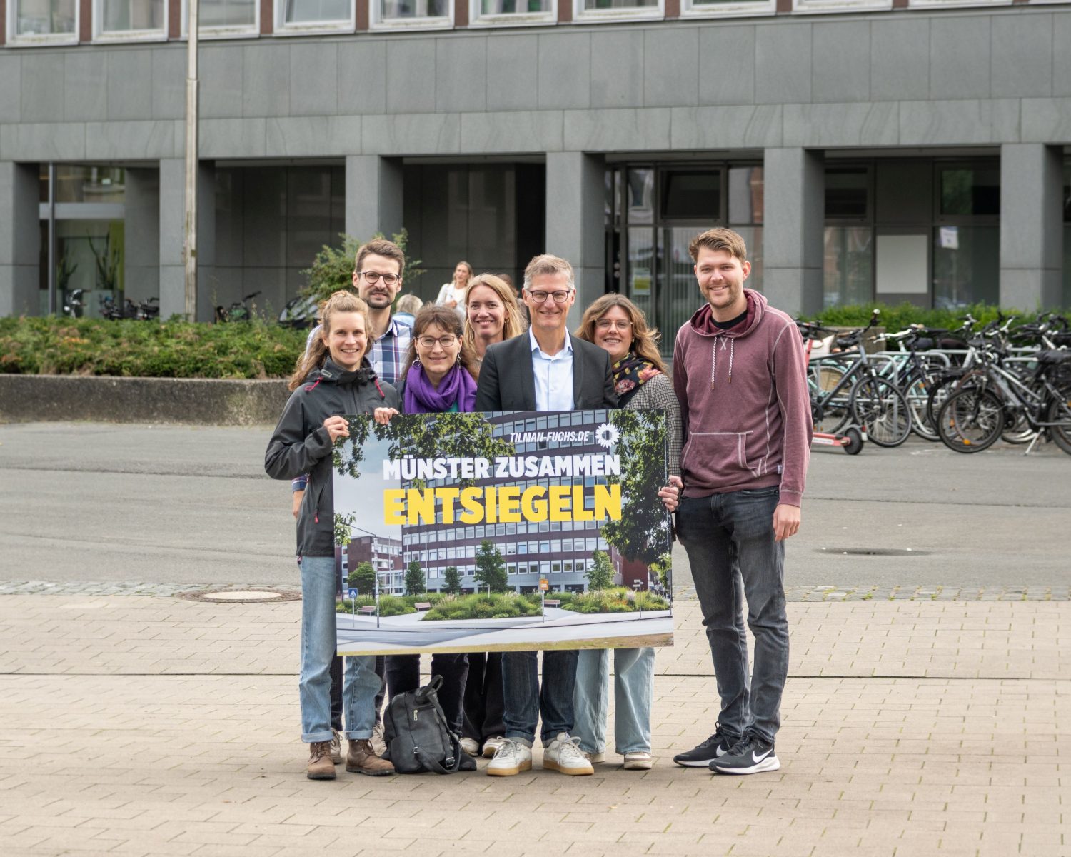 Die Grünen Kandidat*innen mit einem KI-Foto der Entsiegelung vor dem Stadthaus 2