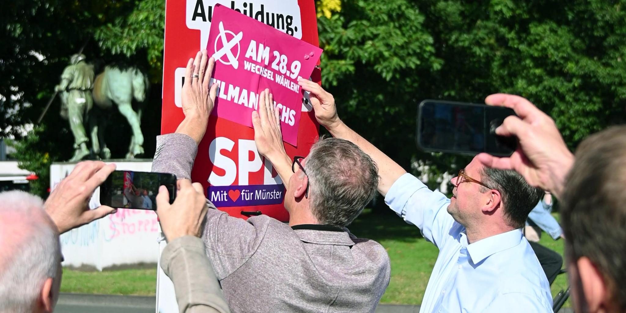 Stephan Brinktrine und Tilman Fuchs beim symbolischen Anbringen der Störer für Tilman Fuchs auf dem Wahlplakat der SPD