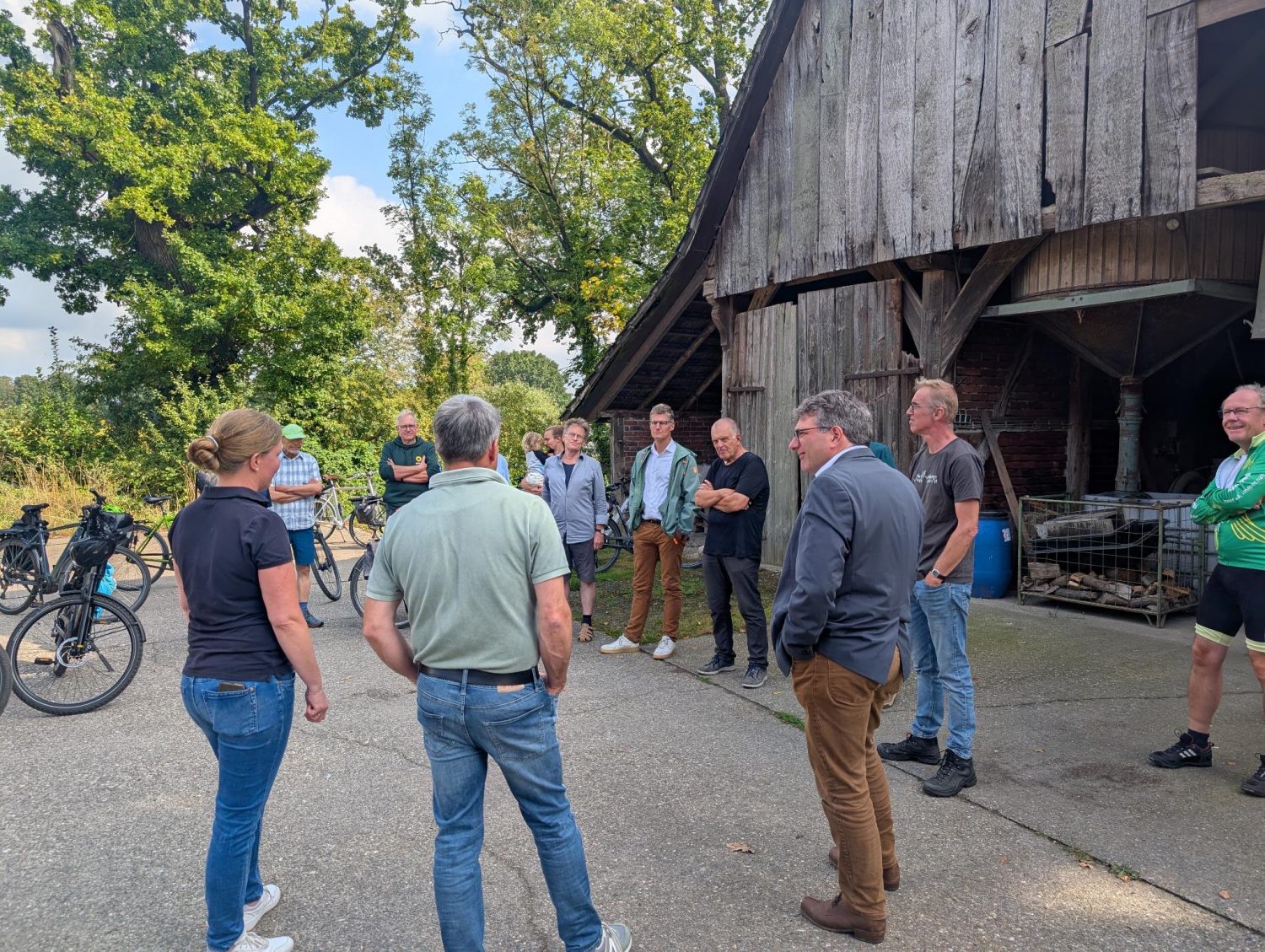 Eine Gruppe von Menschen steht auf einem Bauernhof zusammen und redet