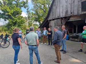 Eine Gruppe von Menschen steht auf einem Bauernhof zusammen und redet